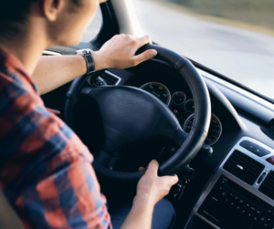 Man driving with both hands on the steering wheel.